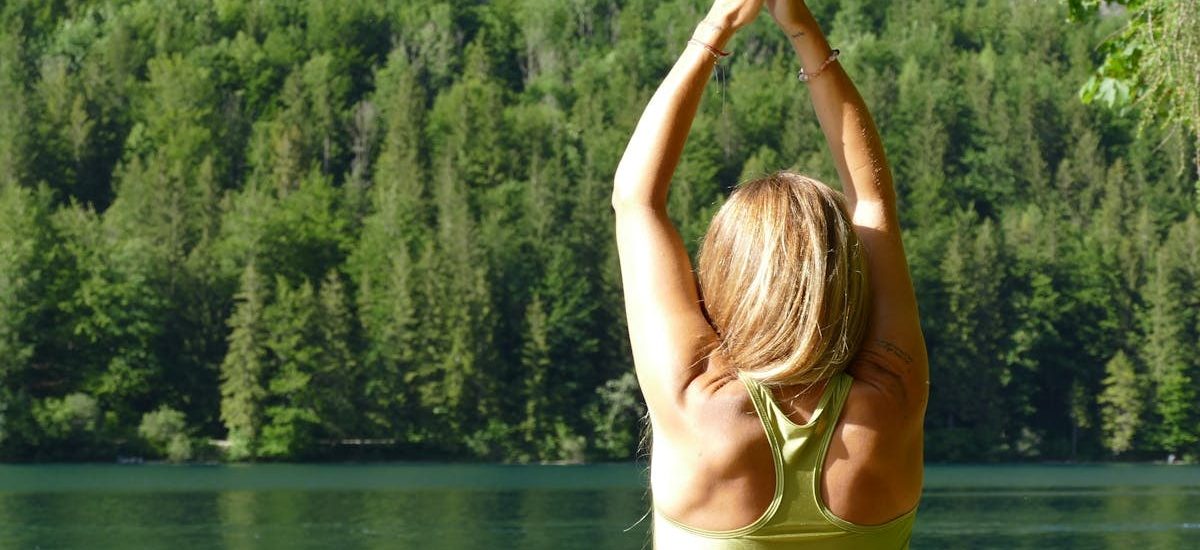 Back view of a woman meditating in a yoga pose by a serene lake in Ebensee, Austria.